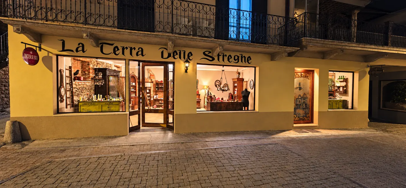 La facciata e l’insegna del negozio La Terra delle Streghe, con le vetrine illuminate